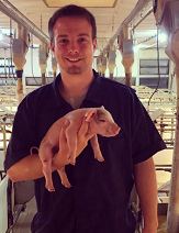 Matthew Rooda Holding a baby pig